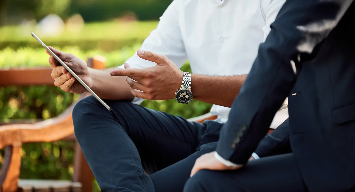 Zwei Personen sitzen auf einer Parkbank und befinden sich scheinbar im Gespräch.