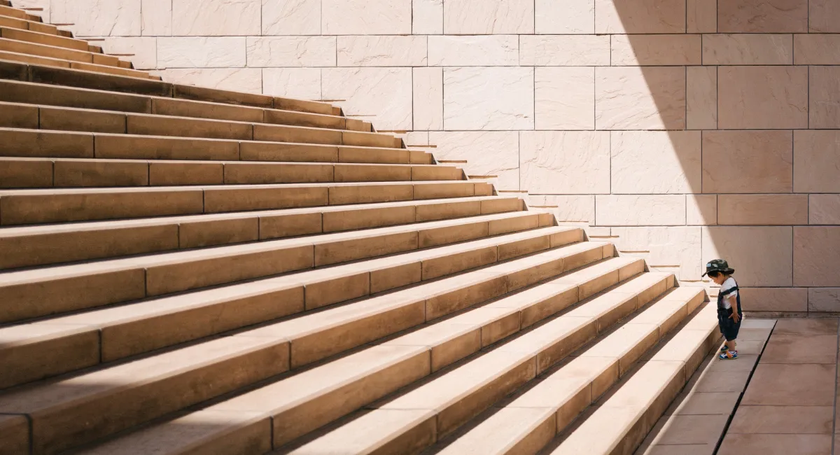 Stehendes Kind vor einer großen Treppe.