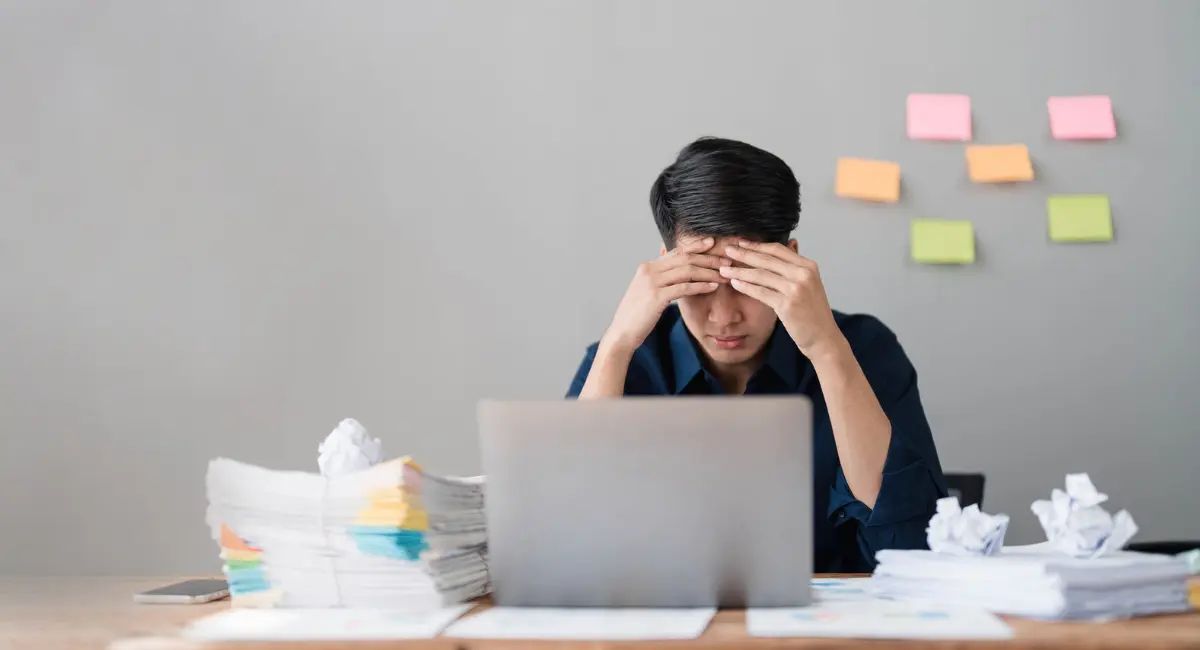 Resilienz im Beruf: Junger Mann sitzt nachdenklich am Schreibtisch vor dem Laptop