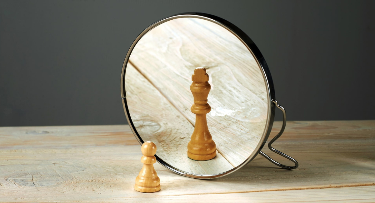 Bauerfigur betrachtet sich im Spiegel und erkennt einen König als Symbol der Selbstreflexion.