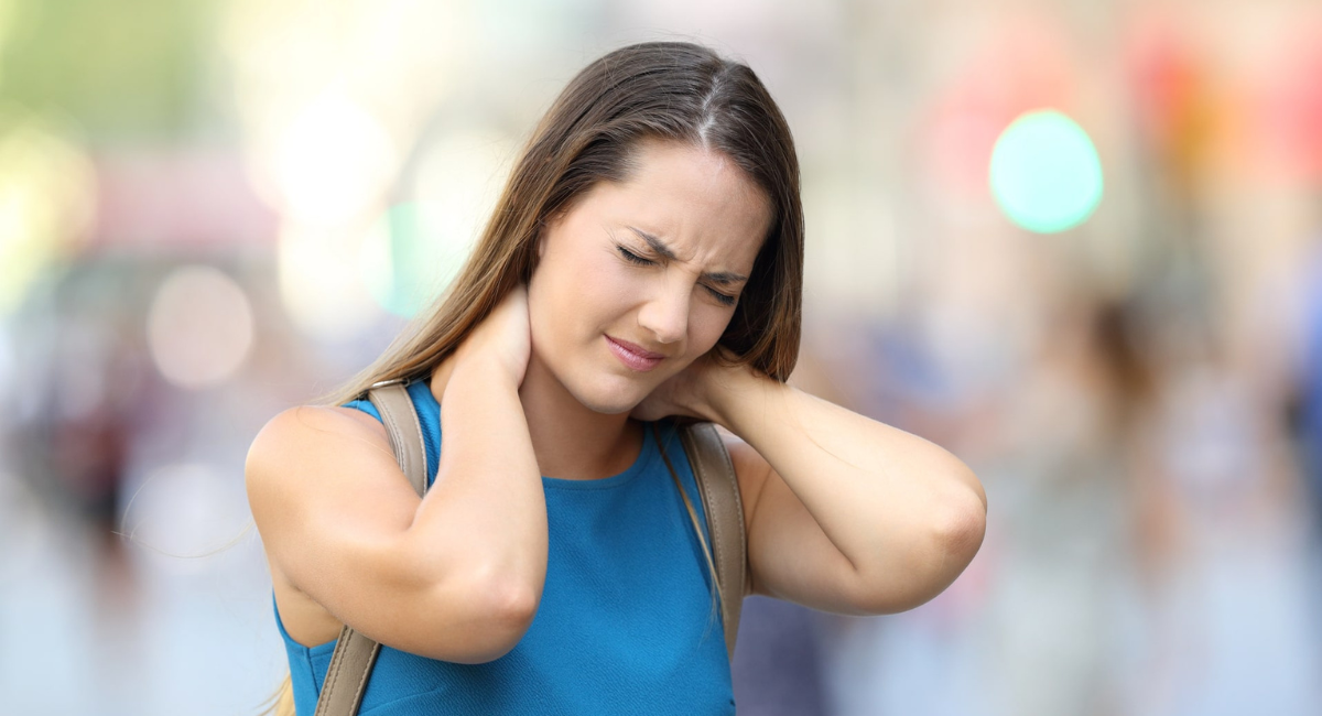 Frau mit körperlichen Stresssymptomen im Nacken